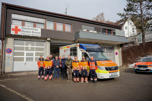 Bild der Eröffnung der Rettungswache Blaustein im Gebäude des Ortsvereins Blaustein. Menschen vor einem Rettungswagen vor der Rettungswache