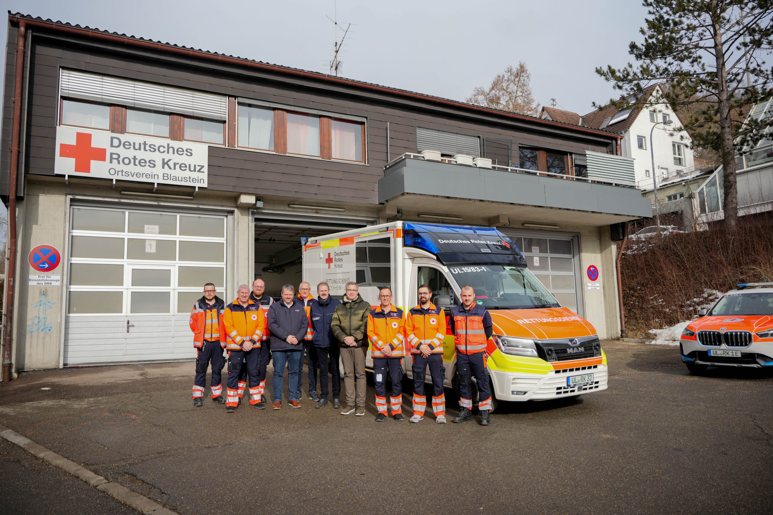 Bild der Eröffnung der Rettungswache Blaustein im Gebäude des Ortsvereins Blaustein. Menschen vor einem Rettungswagen vor der Rettungswache